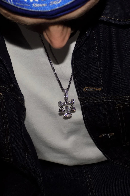 ISOZYGÓS 925 silver balance-scale pendant with moissanite stones worn over a white shirt and dark denim jacket — AETHER
